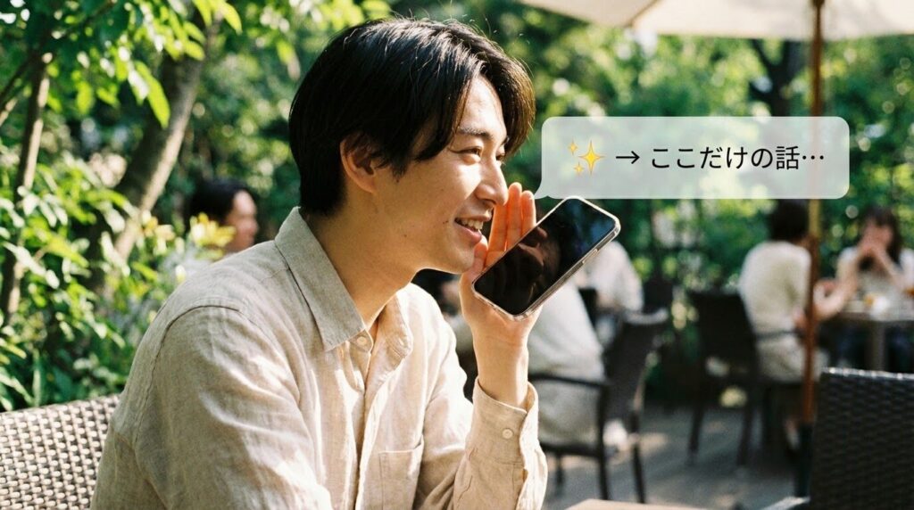 カフェのテラス席で、スマートフォンに優しく話しかけている人の様子。リラックスした雰囲気が伝わる。